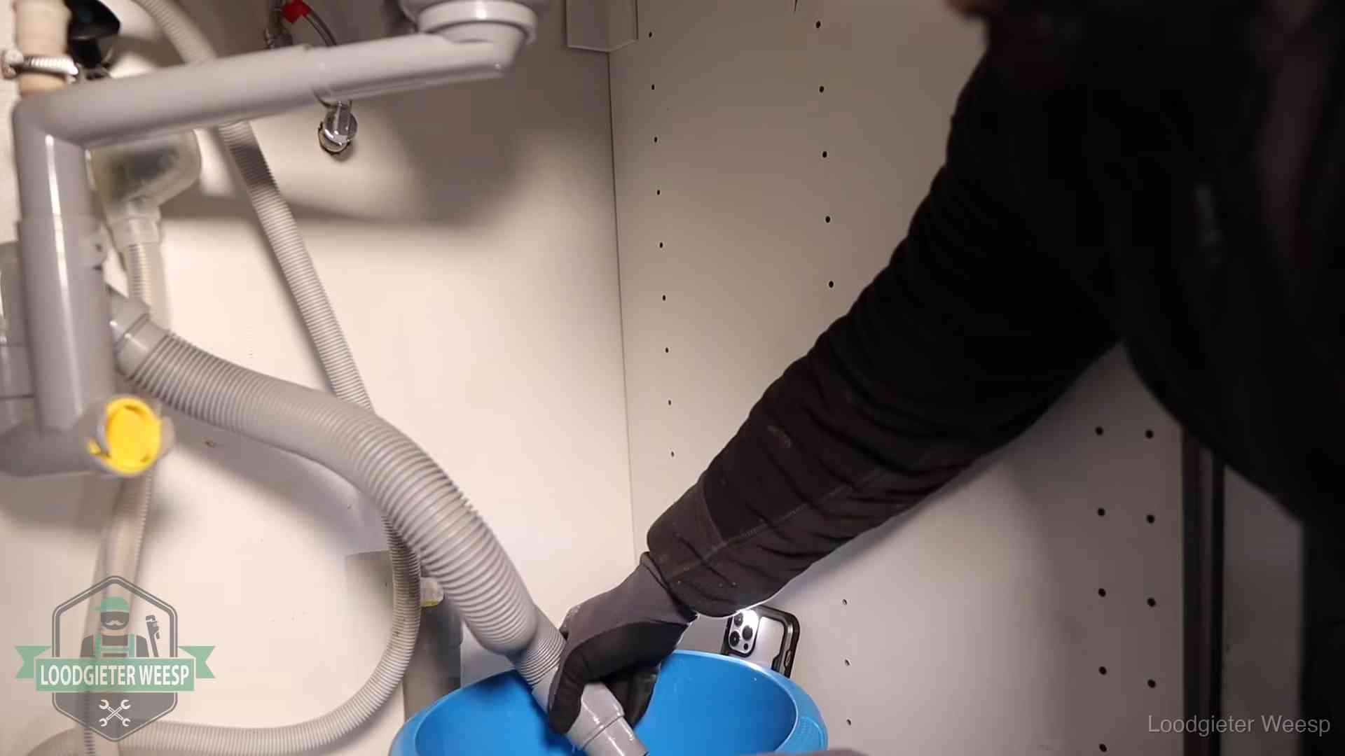 Afvoerslang loopt leeg in een emmer onder de gootsteen in Weesp, een klus die je zelf kunt doen