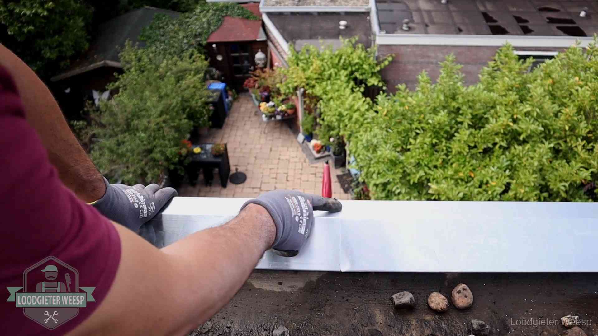 Vakman plaatst een daktrim op de dakrand van een woning in Weesp