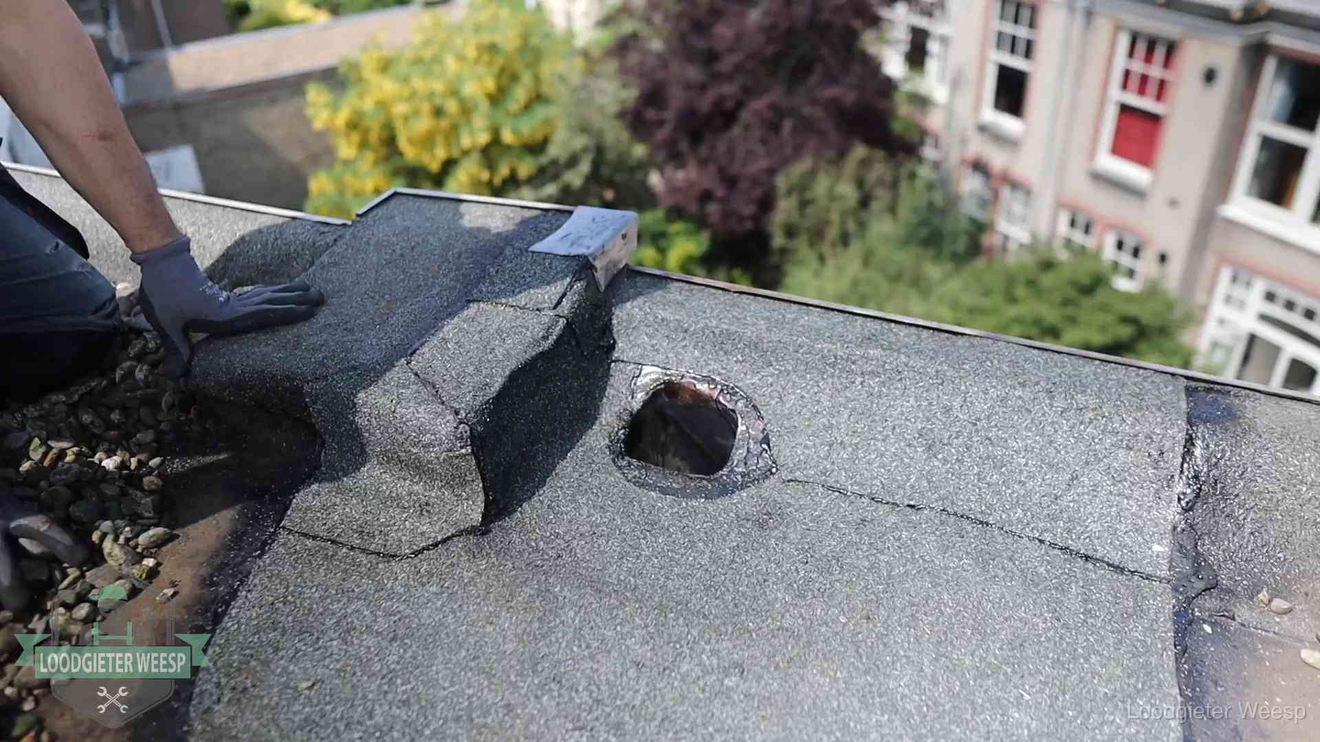 Loodgieter inspecteert een beschadigd bitumen plat dak tijdens een daklekkage-inspectie in Weesp