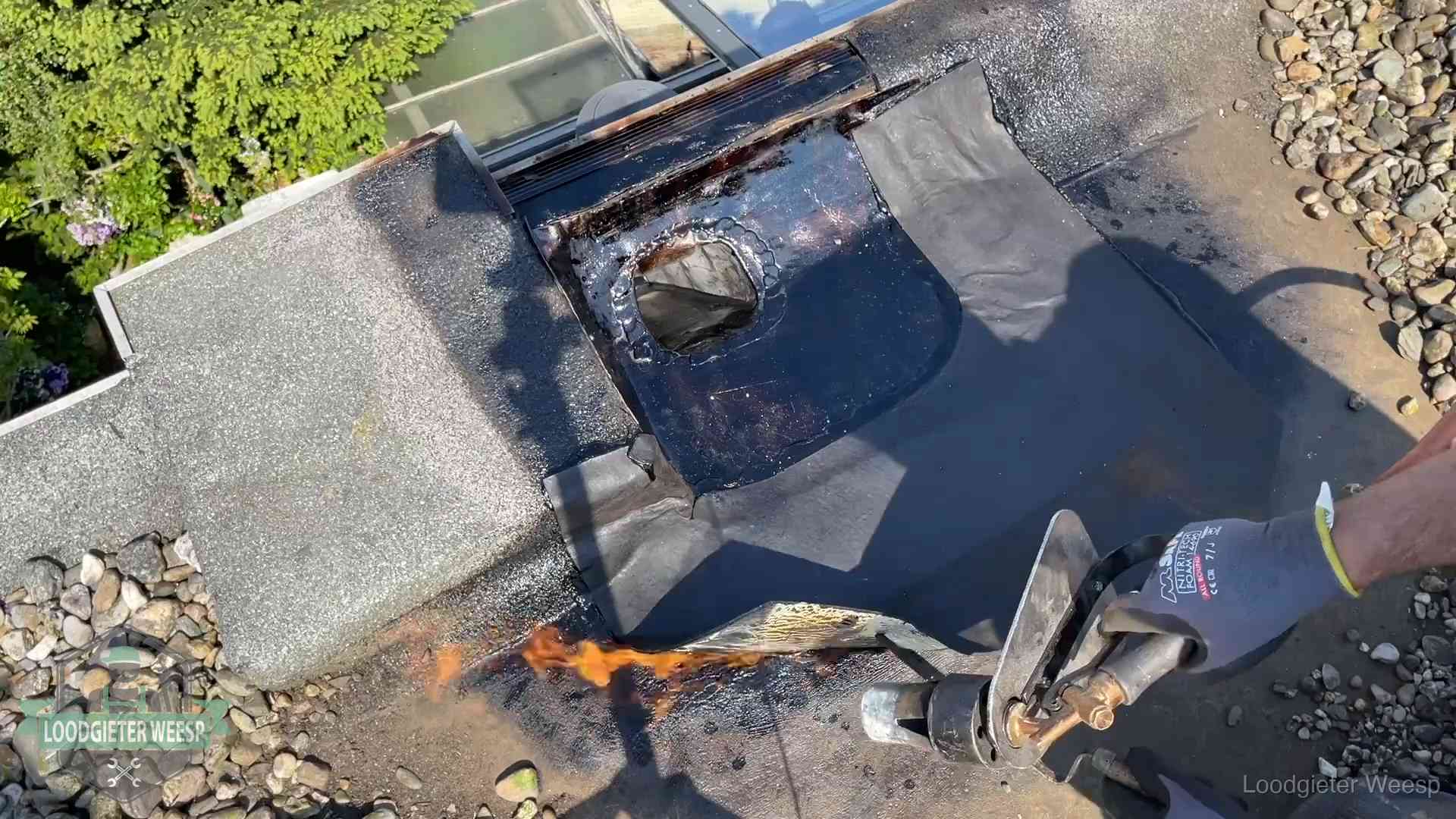 Dakdekker brandt bitumen rond een doorvoer tijdens een daklekkage-reparatie in Weesp