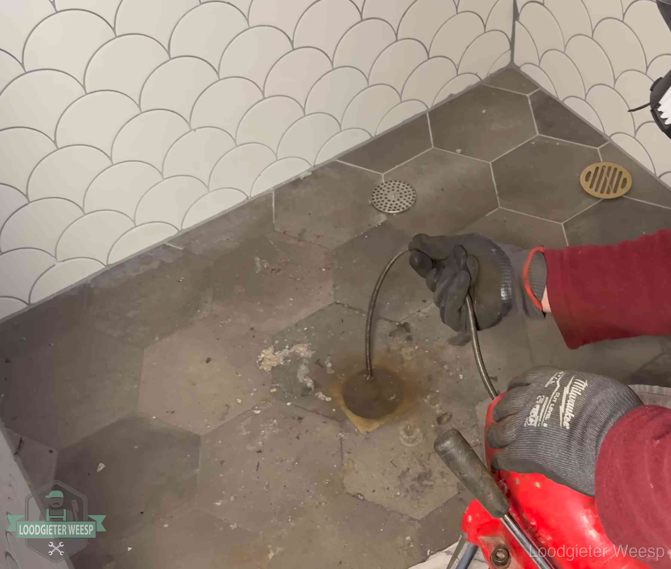 Ontstoppingsveer gaat in een geopend doucheputje in Weesp waar het water omhoogkwam