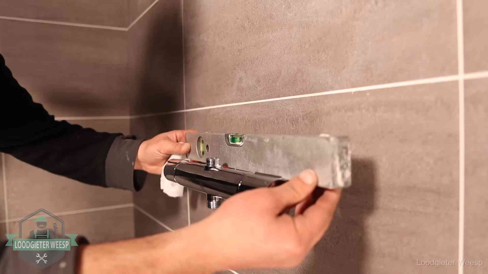 Loodgietersbedrijf voor sanitair in Weesp Loodgieter lijnt een douchekraan uit met een waterpas in een woning in Weesp