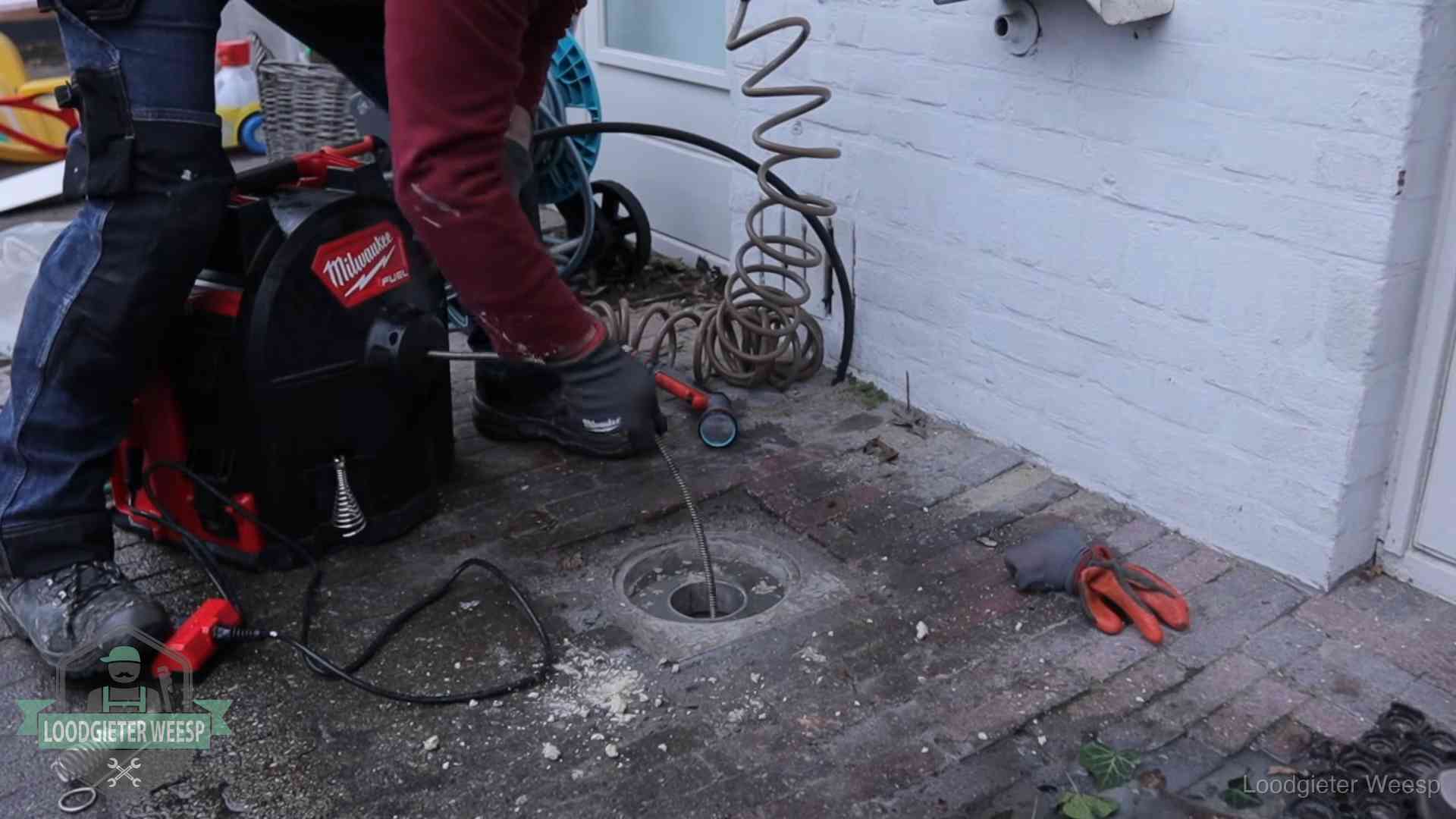 Spiraalmachine bij een ontstoppingsputje in de bestrating in Weesp
