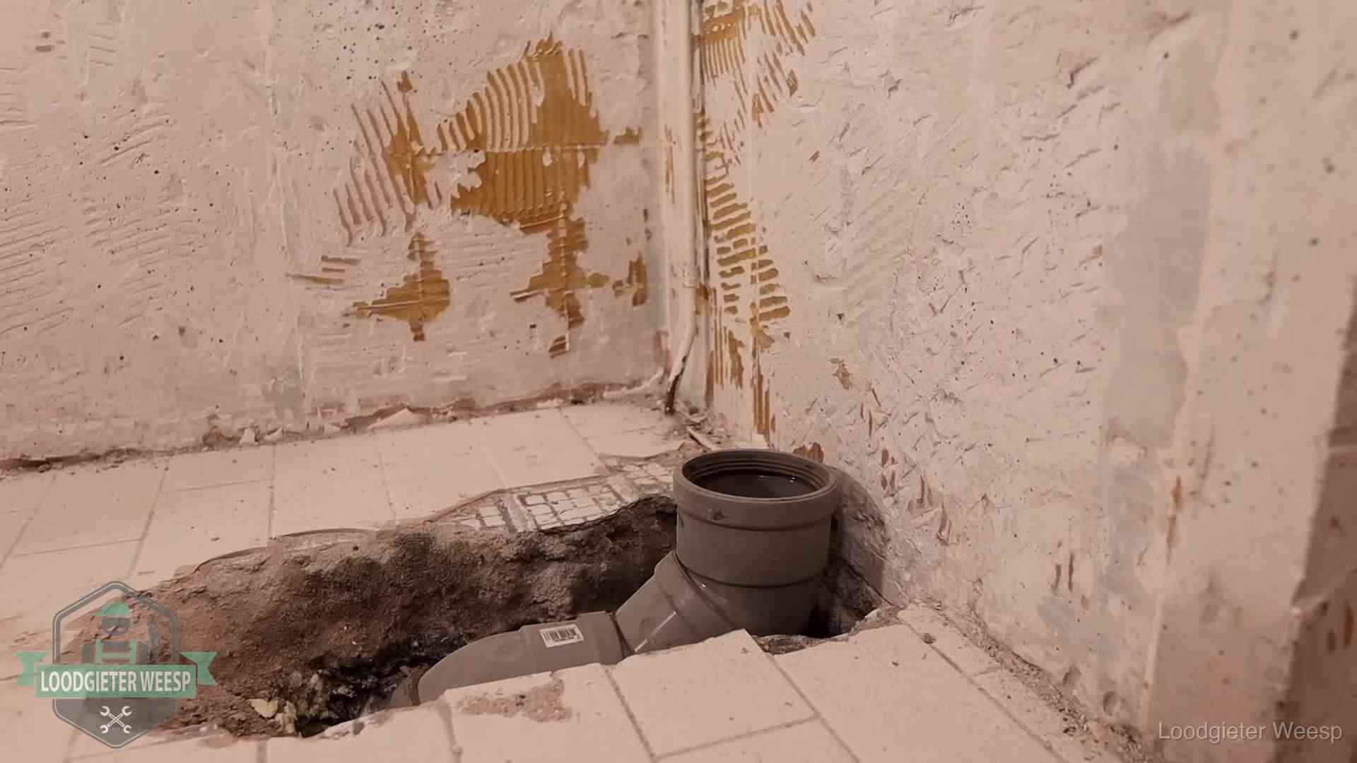 Opengebroken vloer met een nieuwe pvc-rioolbocht in een gegraven sleuf in Weesp