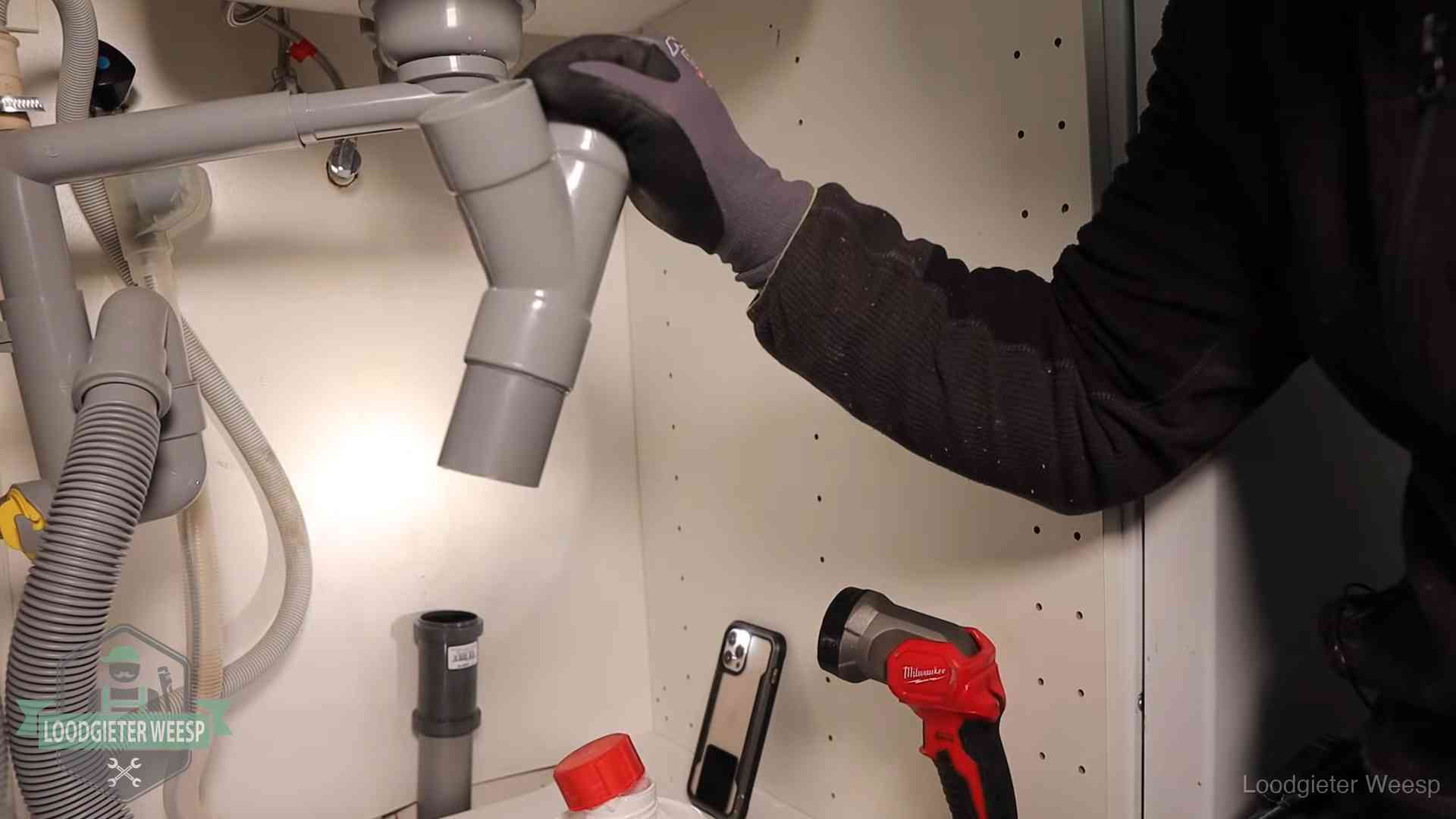 Loodgieter demonteert het sifon- en afvoerwerk onder een gootsteen in Weesp bij stankklachten