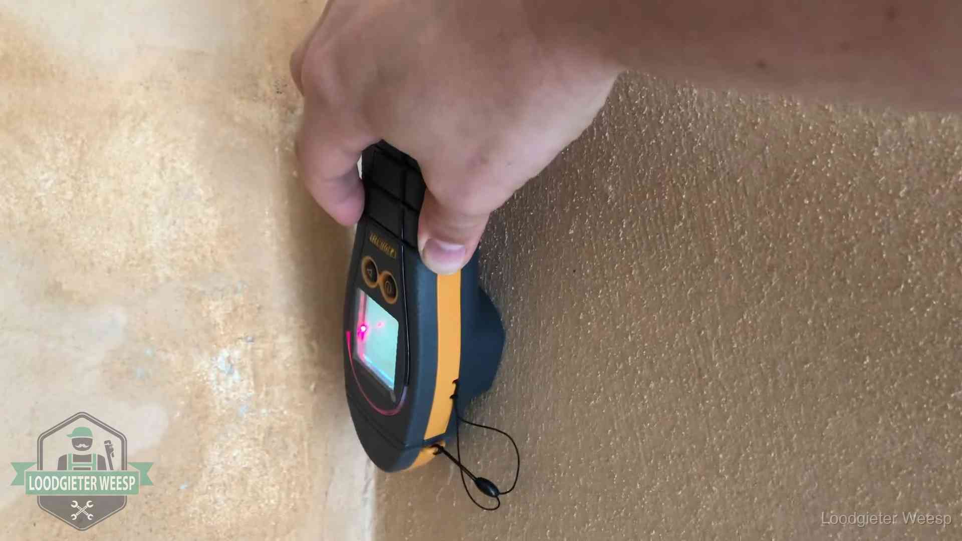 Vochtmeter tegen een muur met vochtplekken tijdens het opsporen van een daklekkage in Weesp